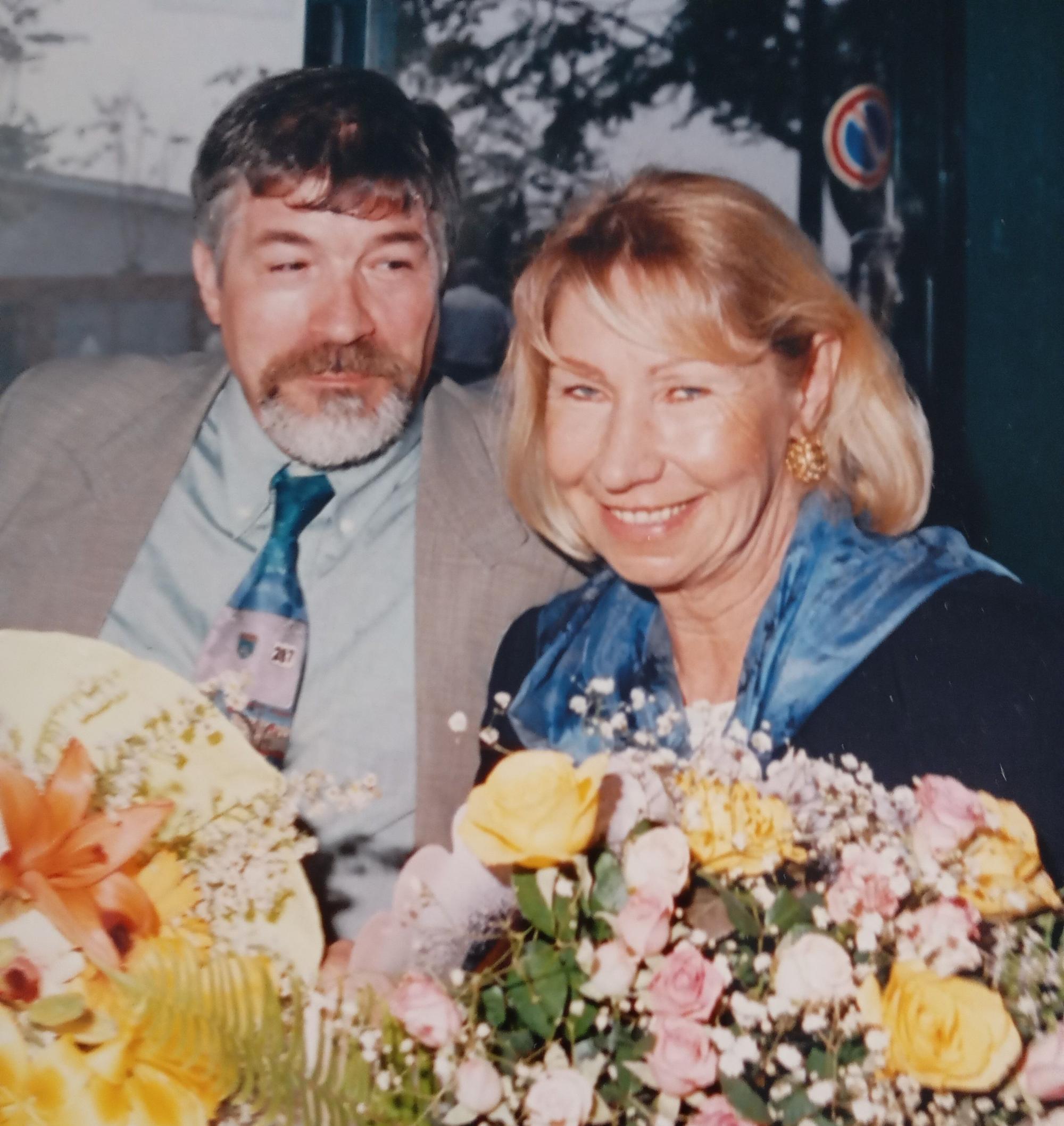Das Bild zeigt ein Ehepaar mit Blumensträußen in den Händen.