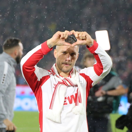 Der Fußballspieler Lukas Podolski steht auf dem Spielfeld und formt mit seinen Fingern ein Herz.