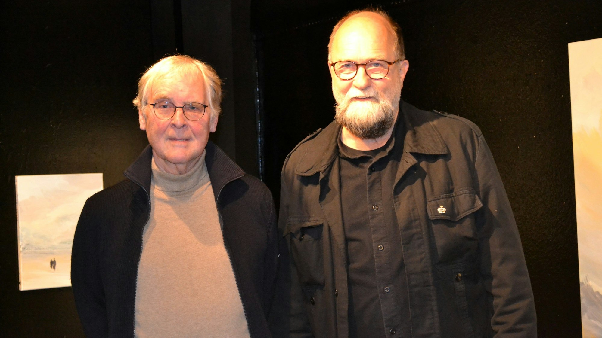 Zwei Männer stehen vor einer schwarzen Wand.