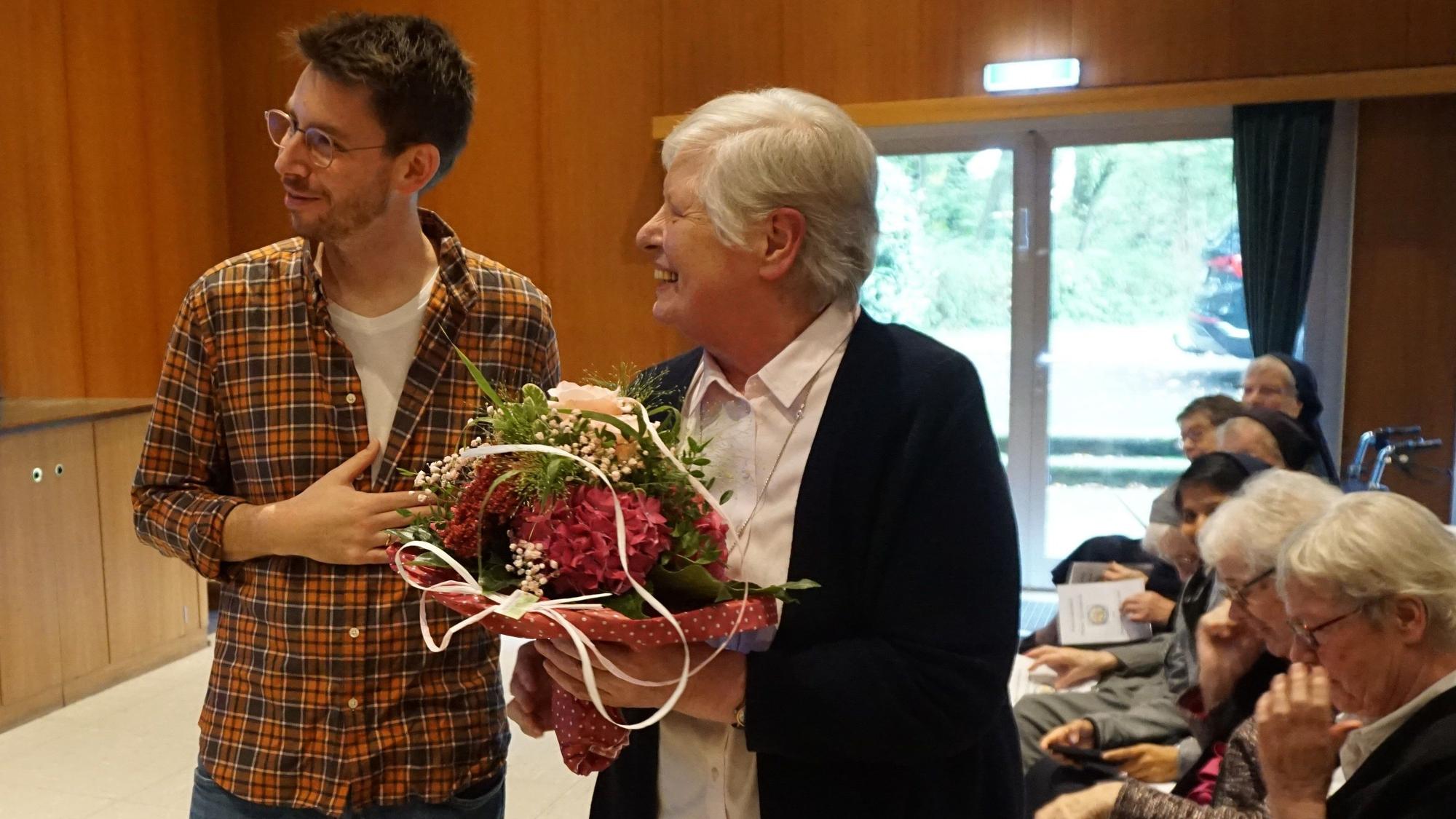 Das Bild zeigt einen Mann und eine Frau mit einem Blumenstrauß in der Hand.