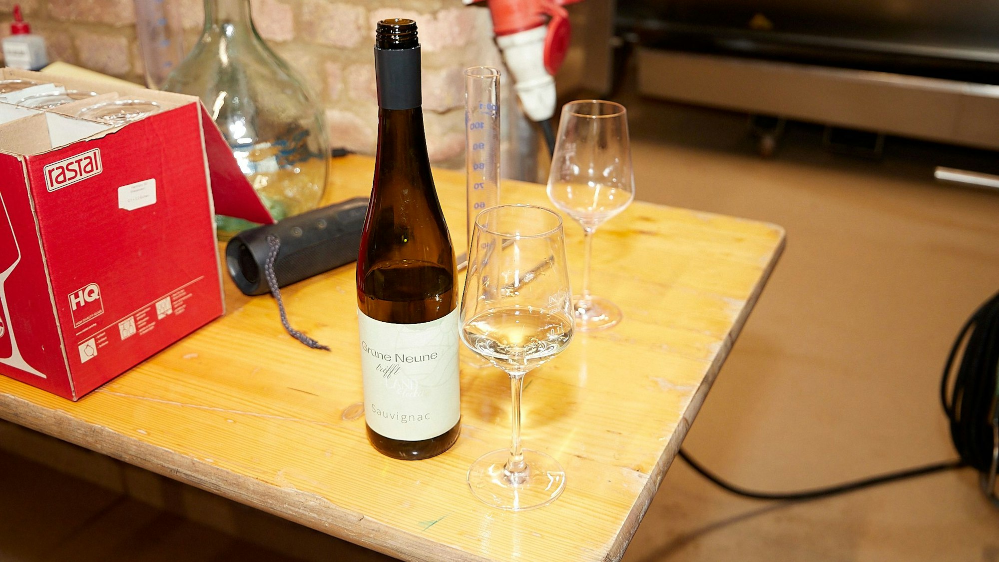 Auf einem Holztisch stehen eine geöffnete Weinflasche und zwei Gläser.