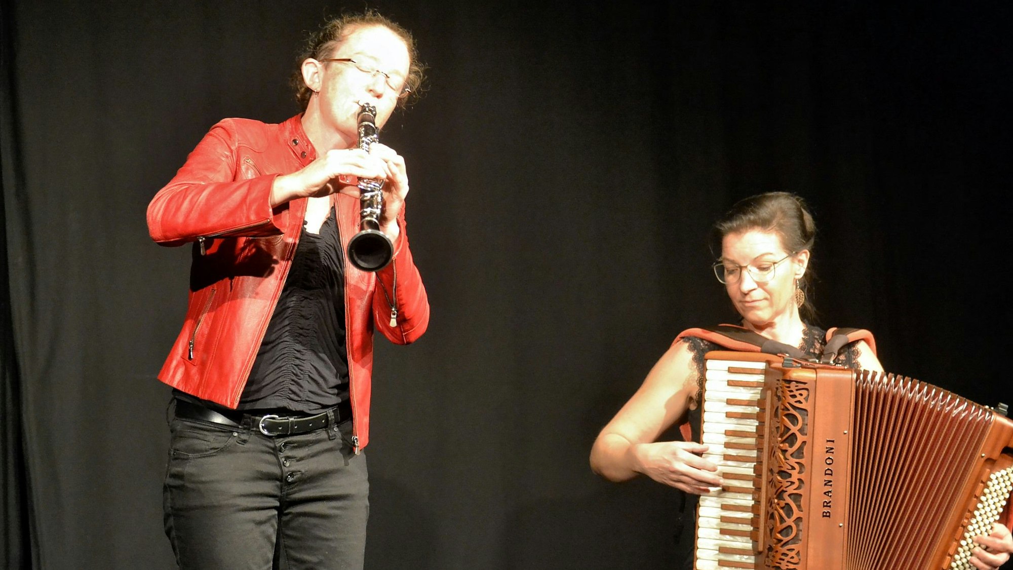 Links steht Susi Evans und spielt Klarinette, rechts sitzt Szilvia Csaranko mit ihrem Akkordeon.