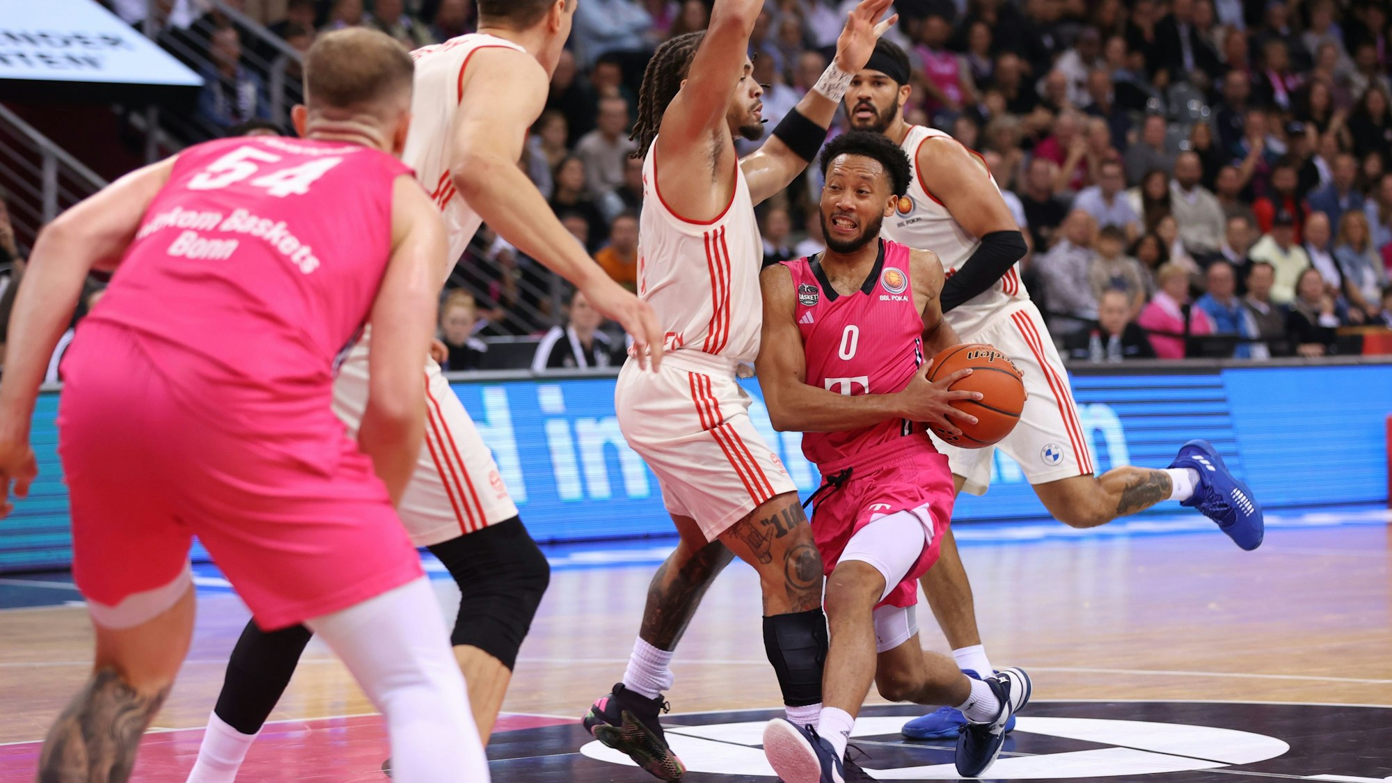 Bonns Darius McGhee (r.) rennt sich in den Münchnern Devin Booker und Joe Voigtmann fest.