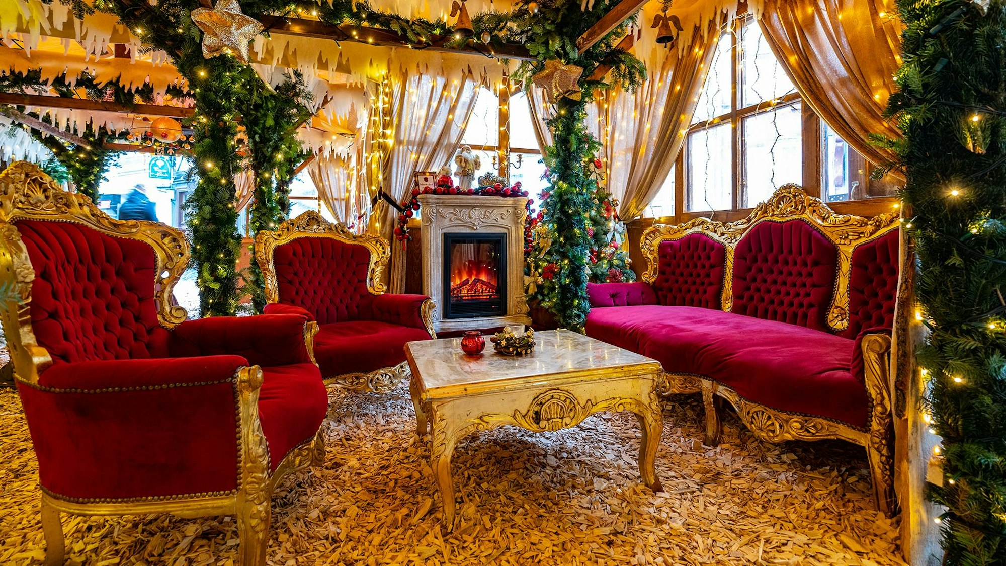 Blick in ein mit roten thronartigen Sesseln geschmücktes Haus auf einem Weihnachtsmarkt.