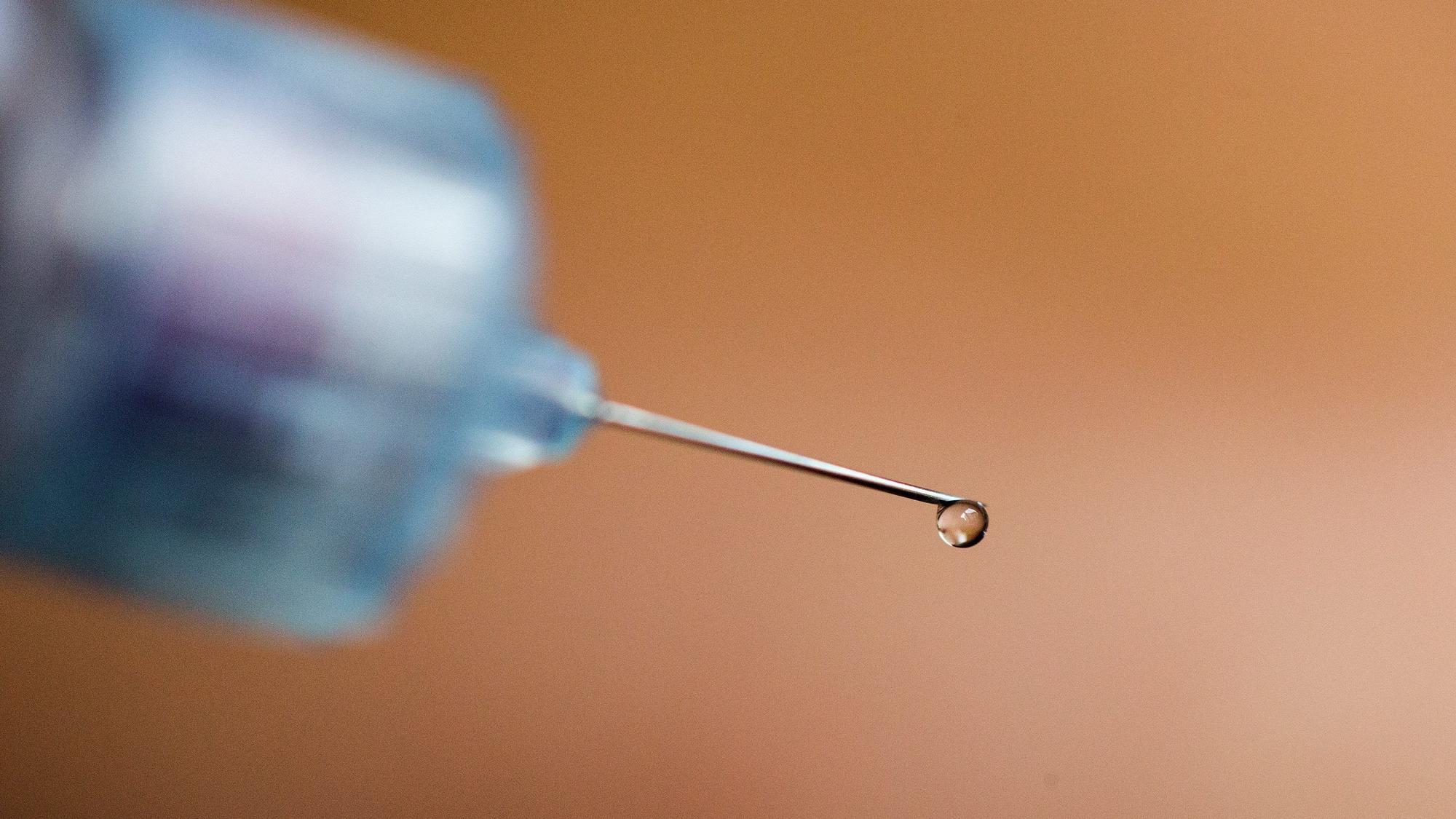 Ein Tropfen Insulin hängt an der Nadelspitze eines Pen.