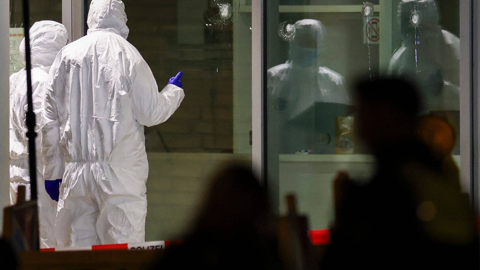 Krefeld: Polizeibeamte der Spurensicherung in weißen Schutzanzügen untersuchen Löcher in Glasscheiben des Kinos. Im Foyer eines großen Kinos am Hauptbahnhof in Krefeld hat die Polizei einen Verdächtigen niedergeschossen.