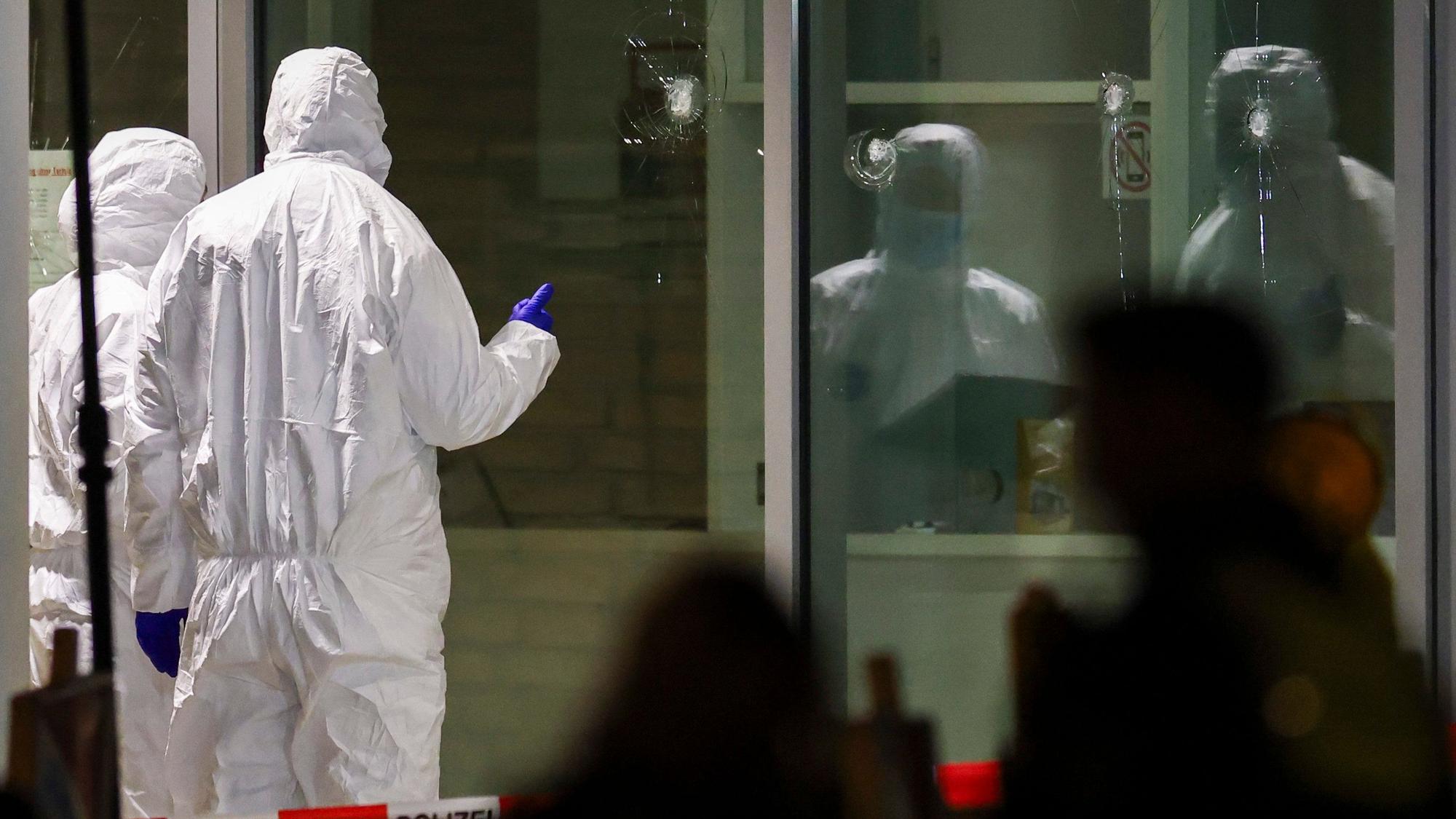 Krefeld: Polizeibeamte der Spurensicherung in weißen Schutzanzügen untersuchen Löcher in Glasscheiben des Kinos. Im Foyer eines großen Kinos am Hauptbahnhof in Krefeld hat die Polizei einen Verdächtigen niedergeschossen.