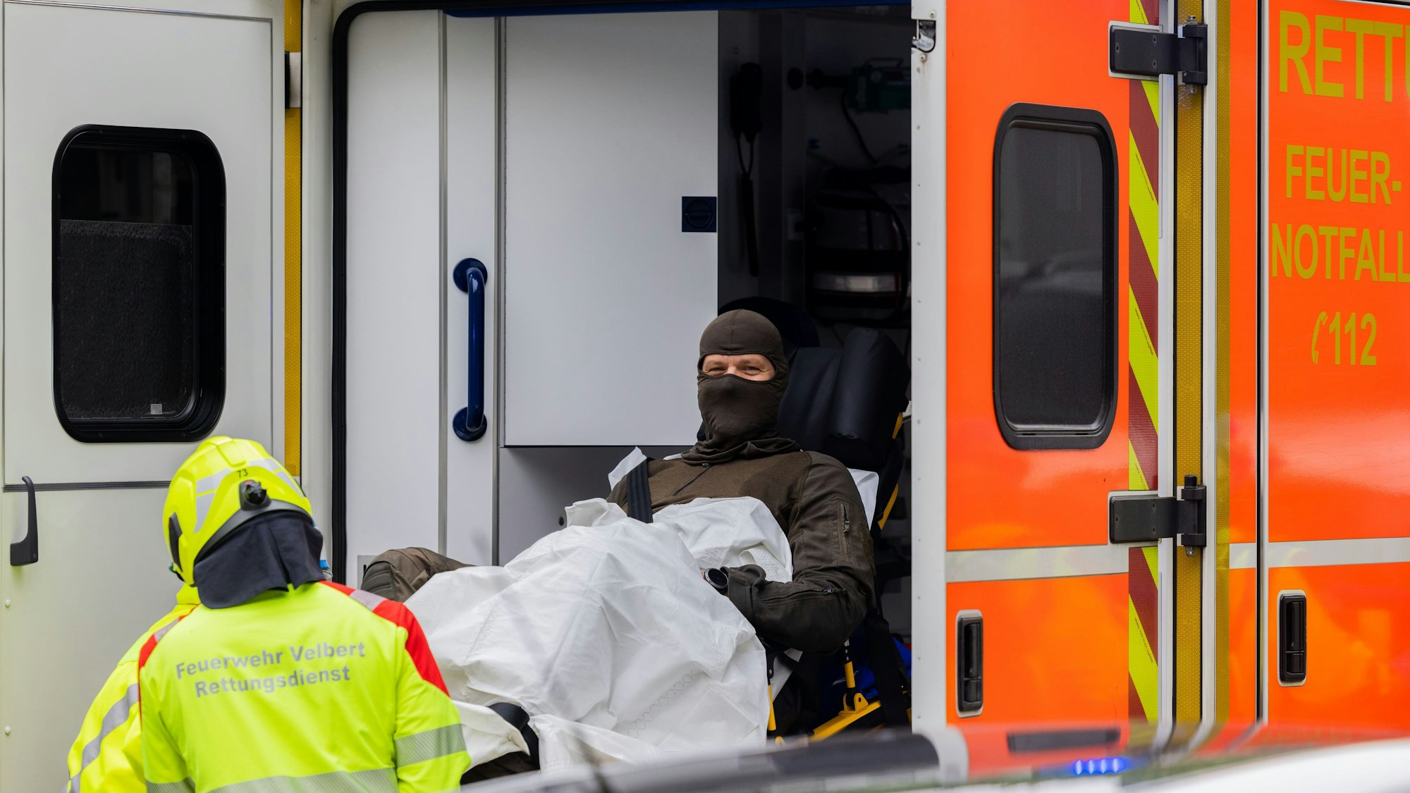 Ein verletzter Polizeibeamter wird in einen Krankenwagen gebracht.