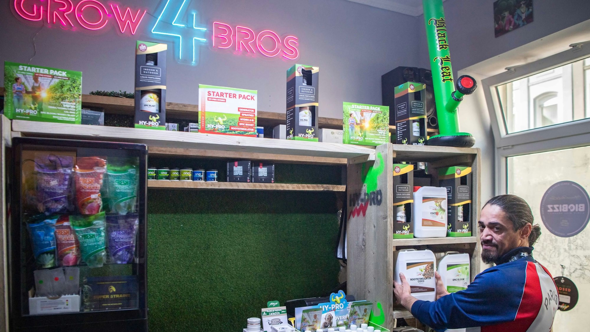 Ein Mann in Trainingsanzug steht in einem Geschäft für Cannabis-Zubehör.