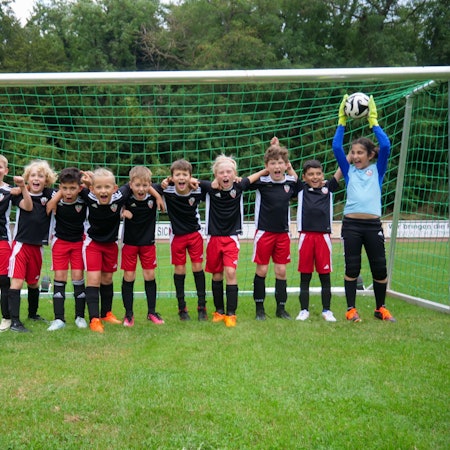 Das Foto zeigt eine Jugendmannschaft im Schulterschluss vor einem Fußballtor.