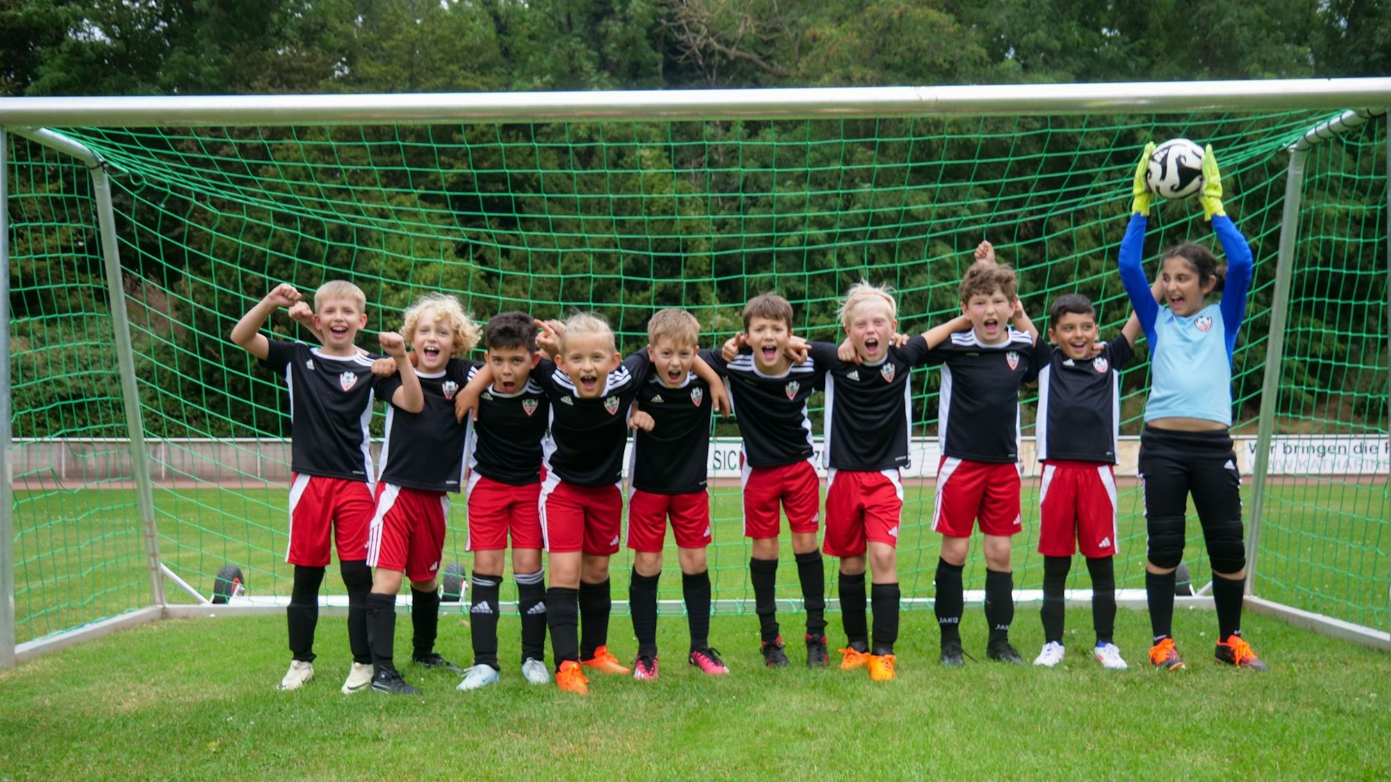 Das Foto zeigt eine Jugendmannschaft im Schulterschluss vor einem Fußballtor.