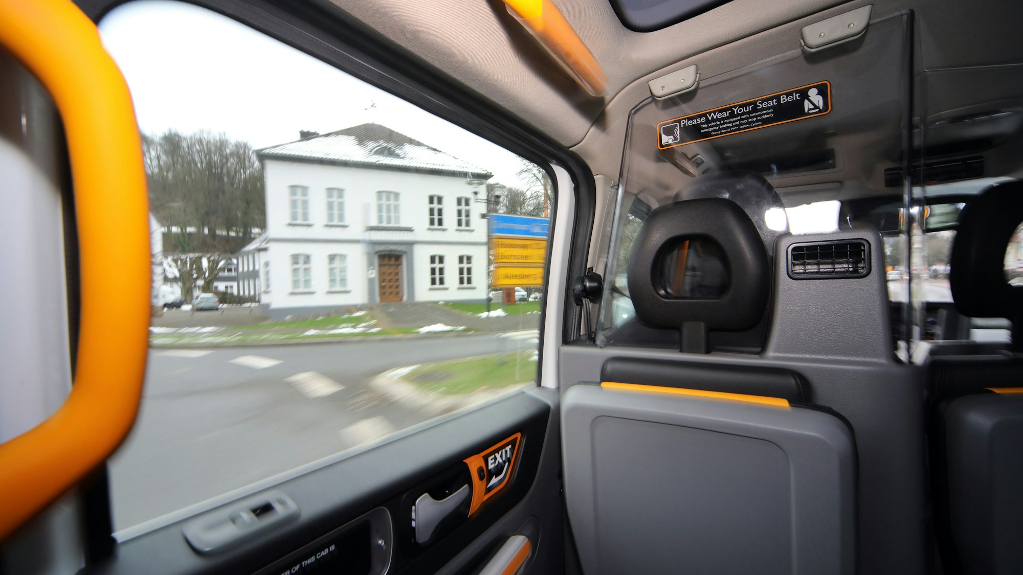 Durch das Fenster eines Sammeltaxis schaut man auf das Odenthaler Rathaus im Winter.