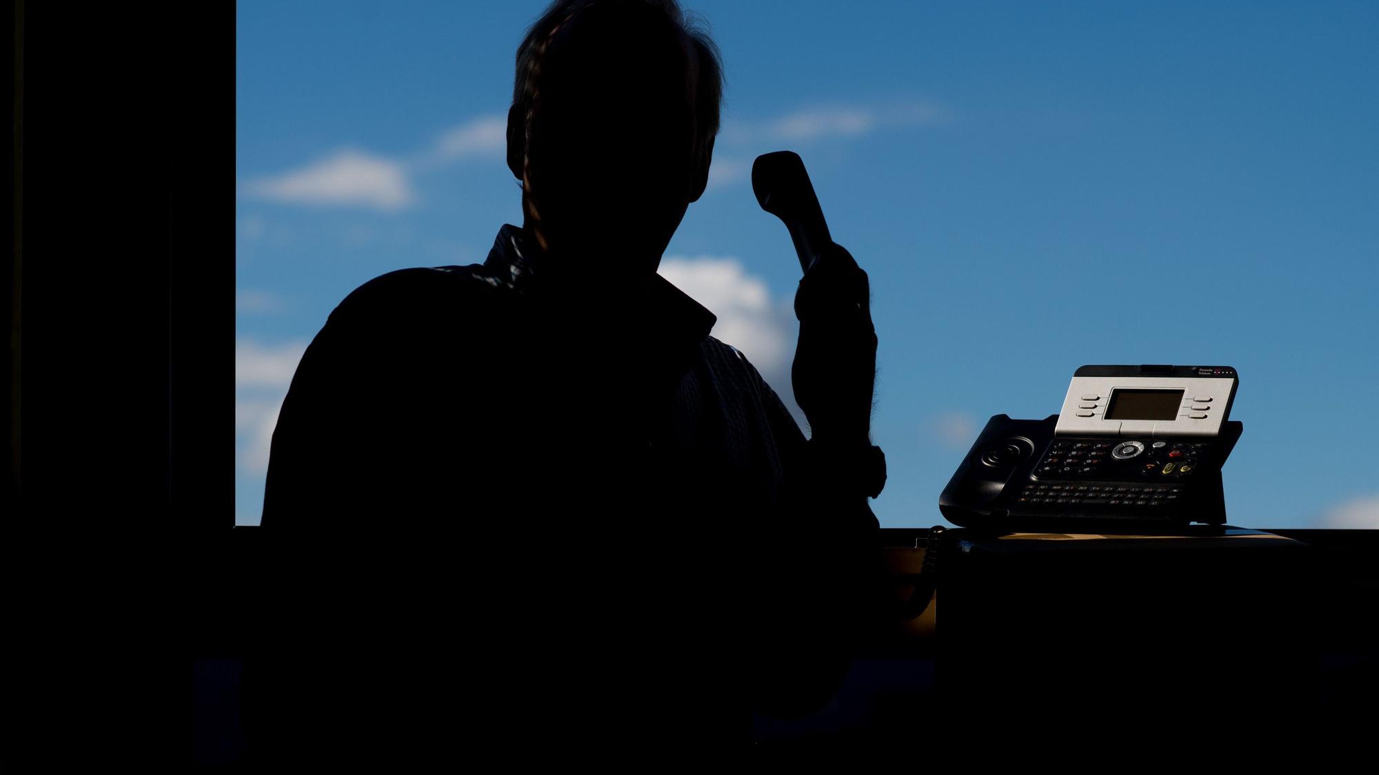 Ein Mann, der nicht zu erkennen ist, hält ein Telefon.