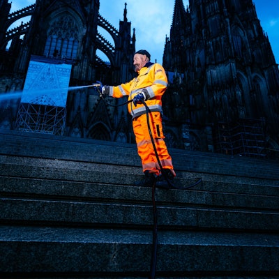 Ein Mitarbeiter der AWB hält einen Schlauch, aus dem Wasser spritzt.