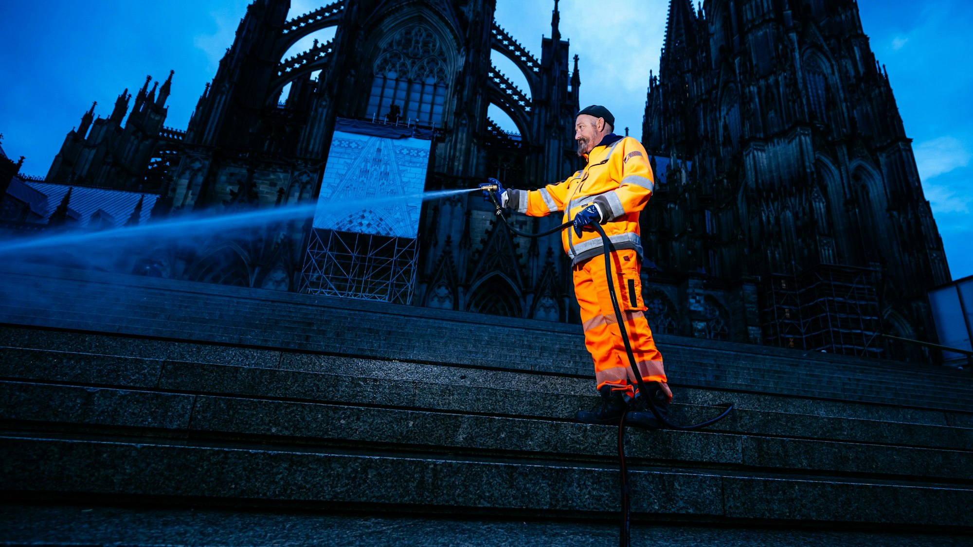 Ein Mitarbeiter der AWB hält einen Schlauch, aus dem Wasser spritzt.