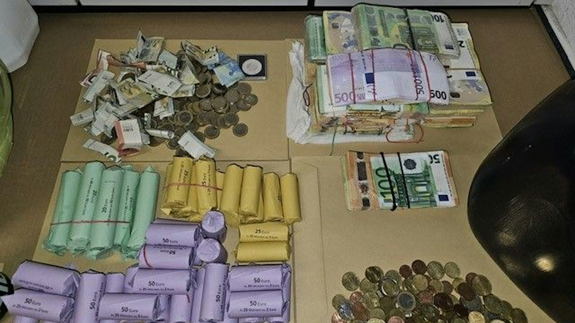 Geld in Form von Scheinen, Münzgeld und gerollte Münzen liegen auf einem Tisch.