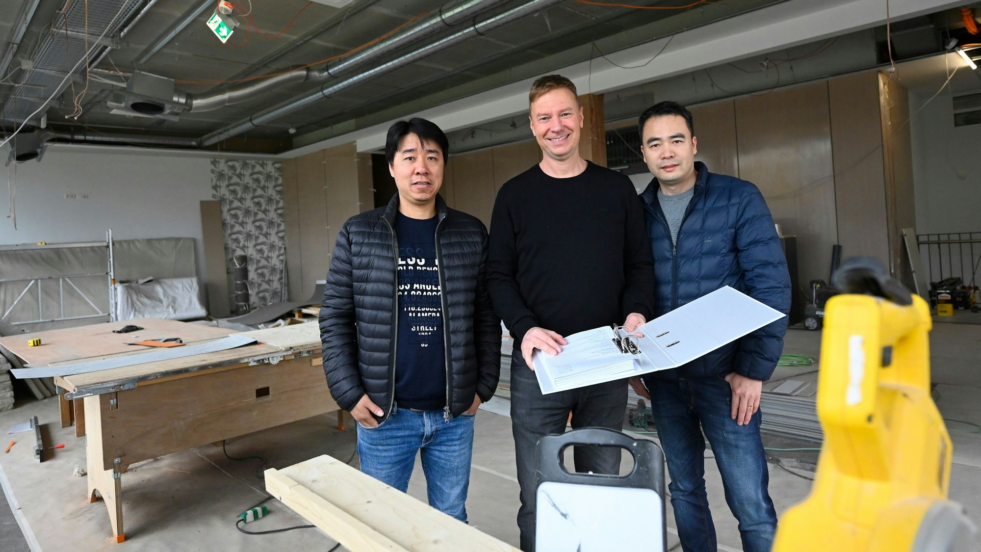 Eigentümer Michael Korthaus und die Gastronomen Fuxing Liu (l.) und Qiang Xu stehen im Rohbau, in dem ein Restaurant entstehen soll.