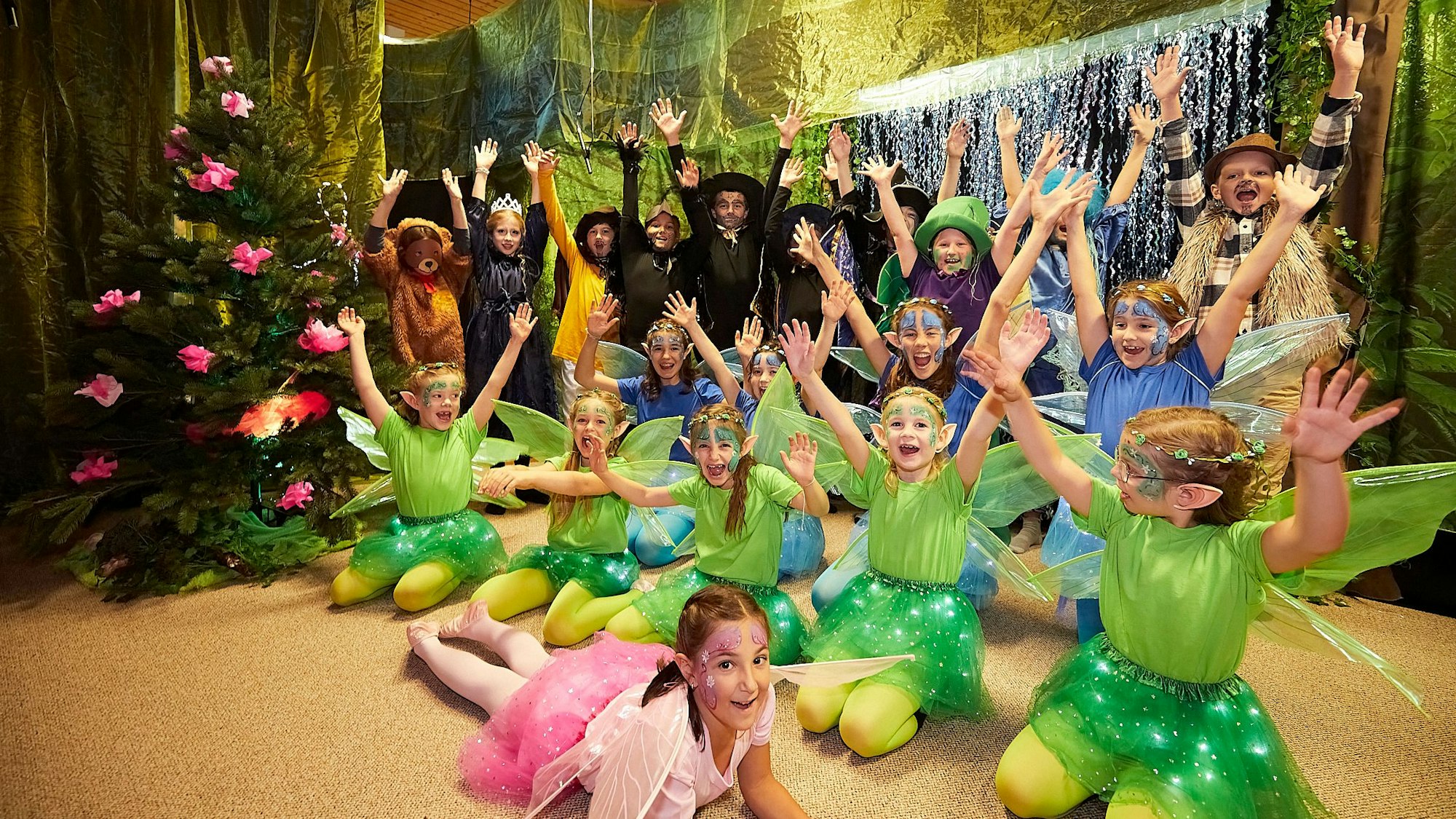 Kinder, die als Elfen und Hexen verkleidet sind, knien und stehen auf der Bühne.