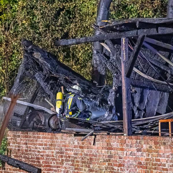 Ein Feuerwehrmann mit Atemschutz vor einem ausgebrannten Gebäude.