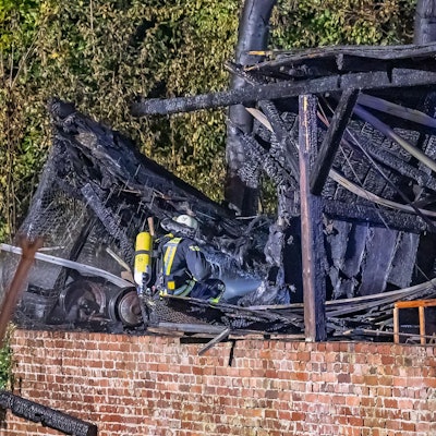 Ein Feuerwehrmann mit Atemschutz vor einem ausgebrannten Gebäude.