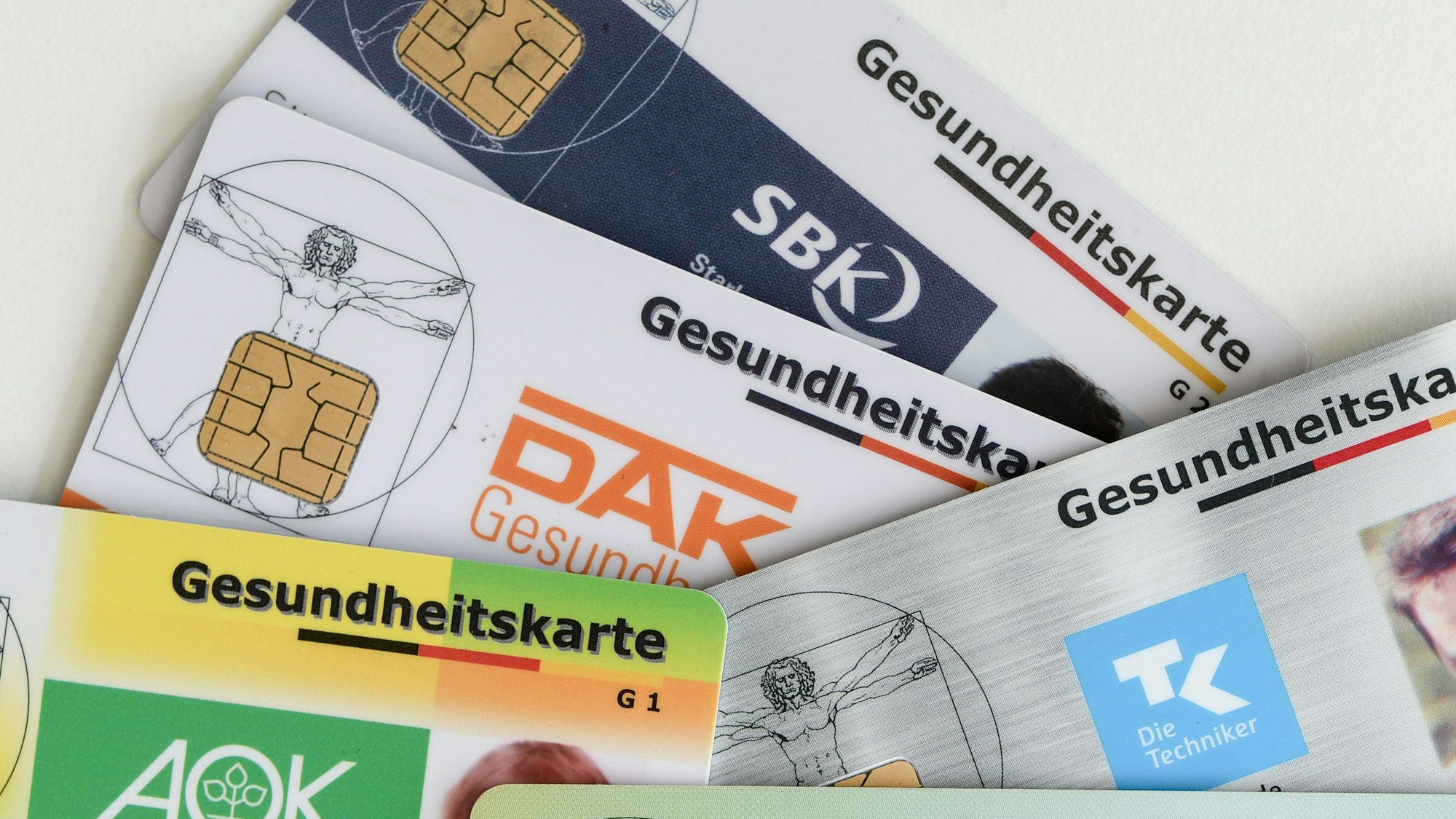 Gesundheitskarten verschiedener Krankenkassen liegen auf einem Tisch.