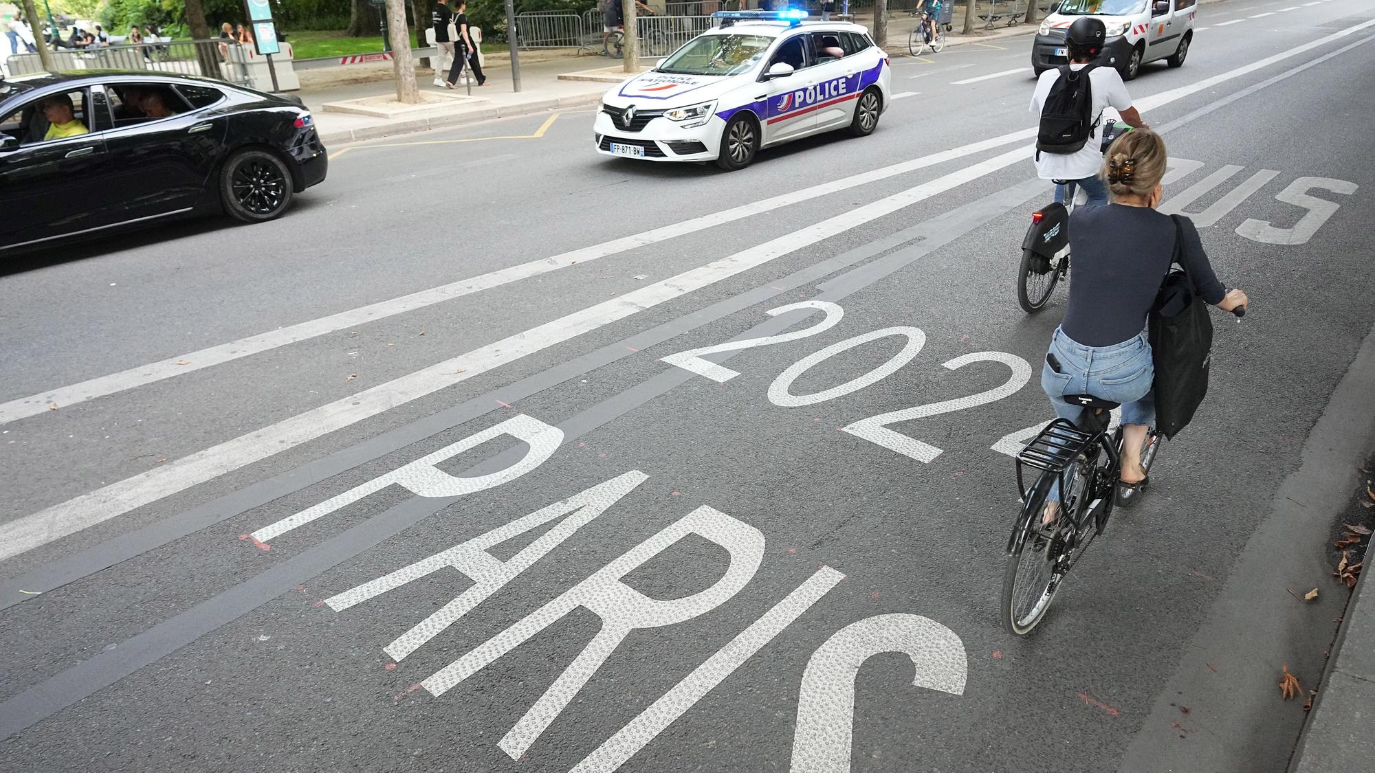 Fahrradfahrer fahren auf einer Busspur an einem Polizeiwagen vorbei.