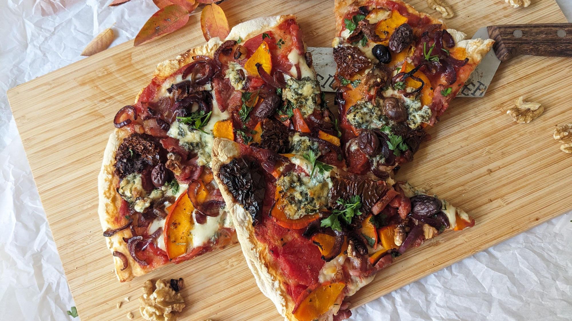Eine in Stücke geschnittene Pizza liegt auf einem Holzbrett.