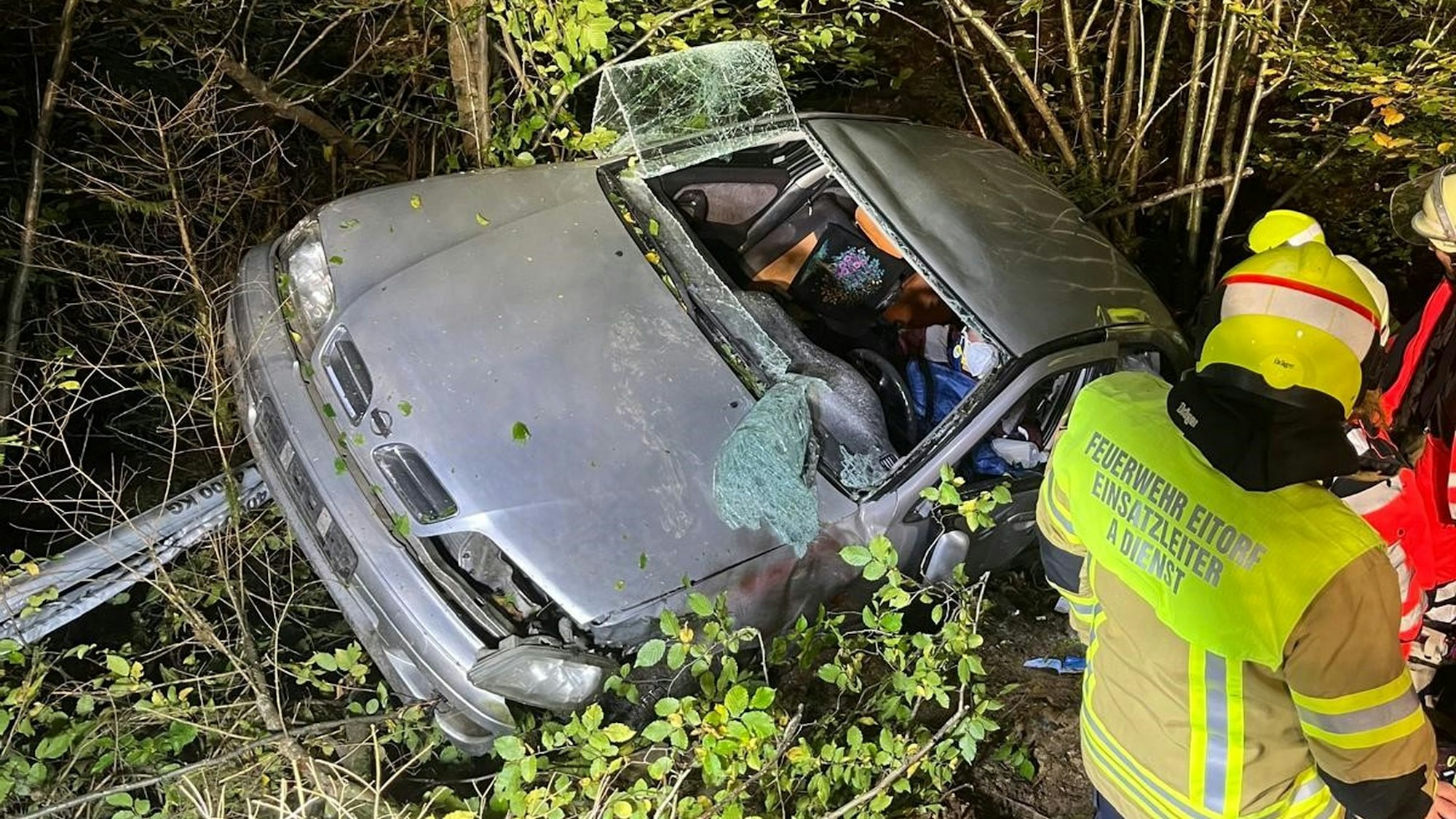 Feuerwehrleute versuchen, zwei Menschen aus einem stark beschädigten Auto zu befreien.