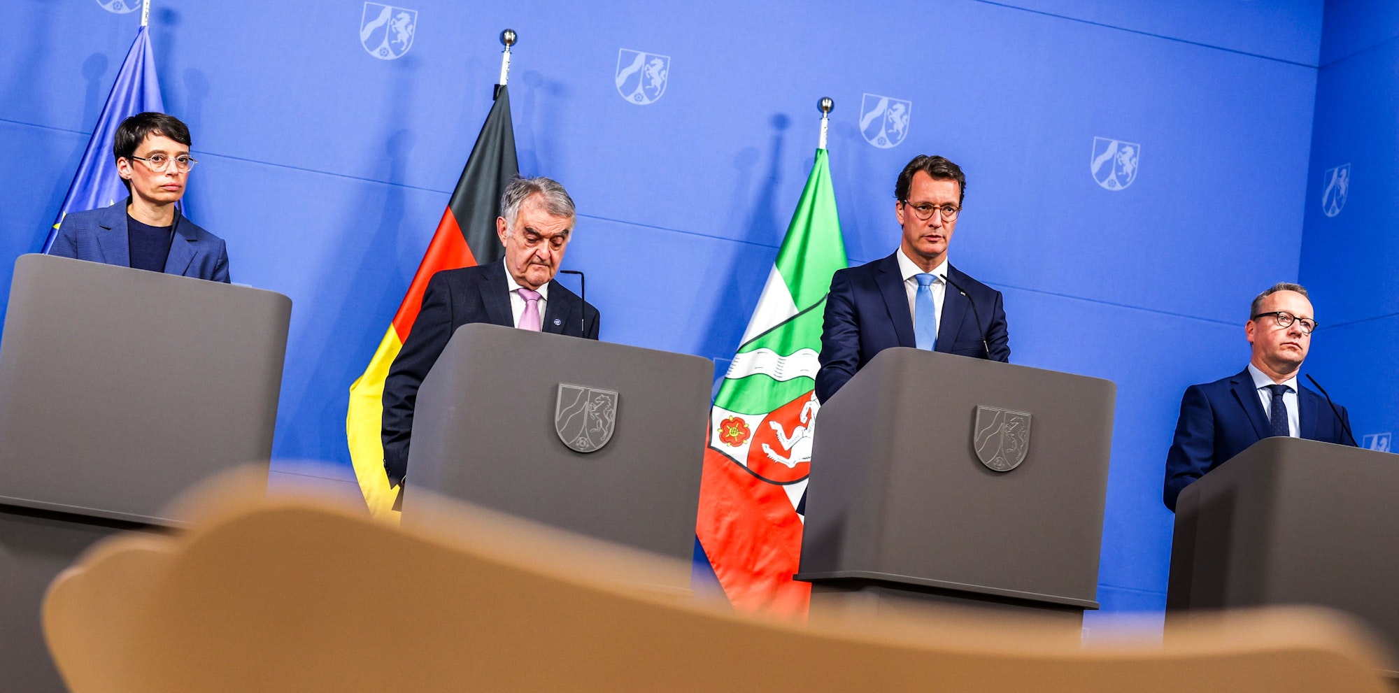 Josefine Paul, Herbert Reul, Hendrik Wüst und Benjamin Limbach stehen hinter Pulten.