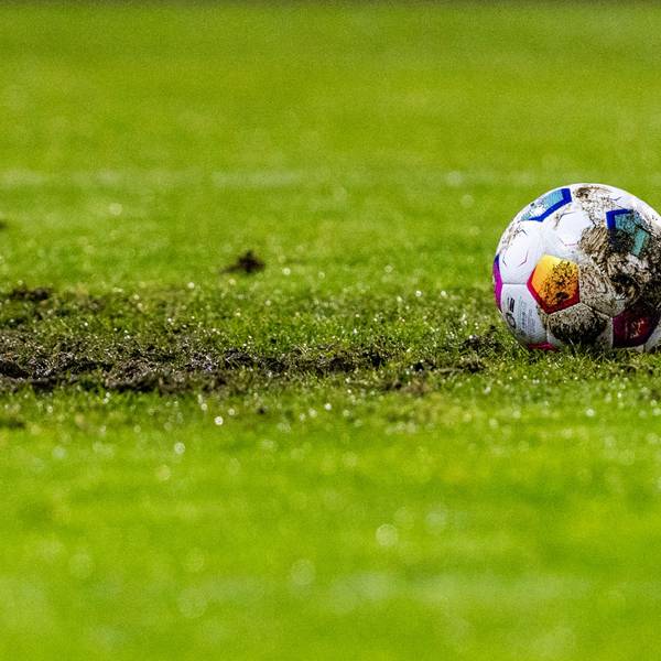 Ein Fußball liegt am Elfmeterpunkt im matschigen Rasen.