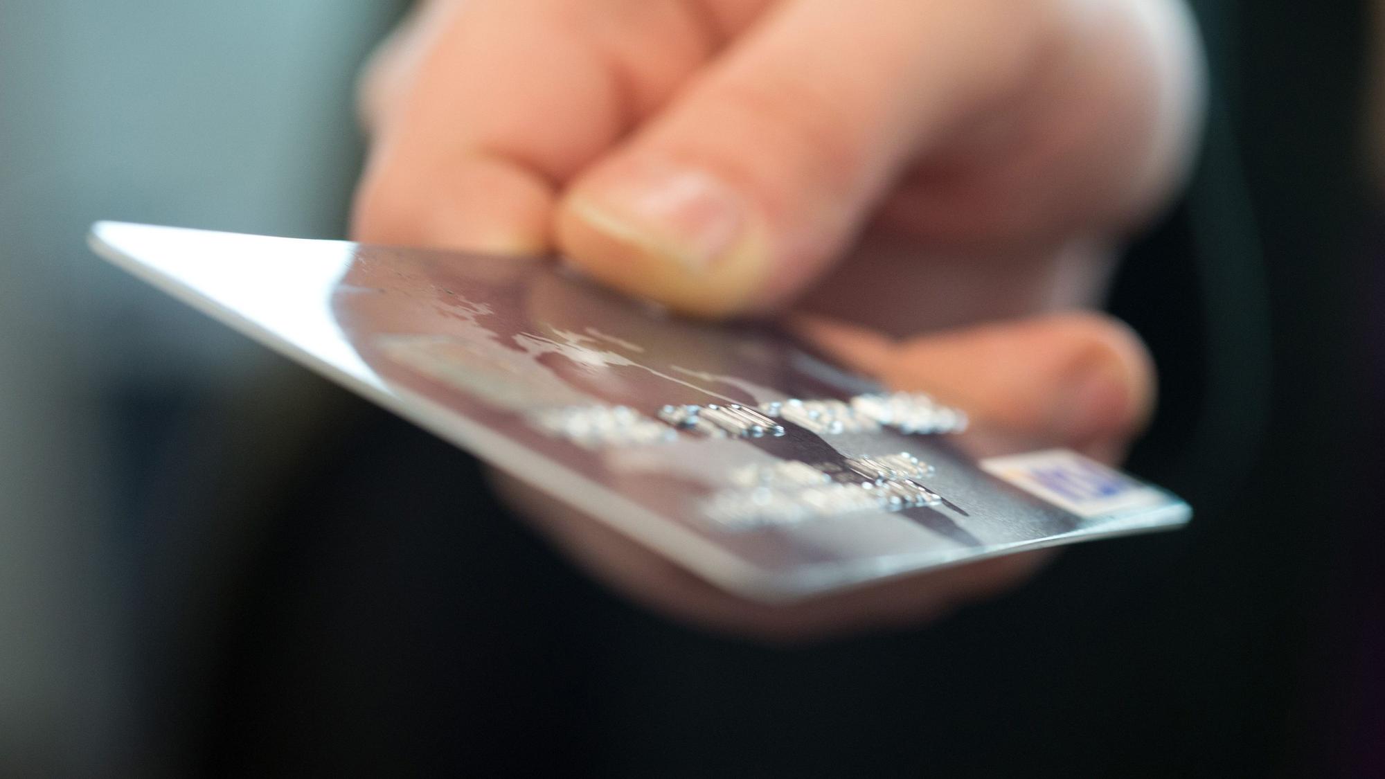 Eine Frau hält eine Bankkarte in der Hand.