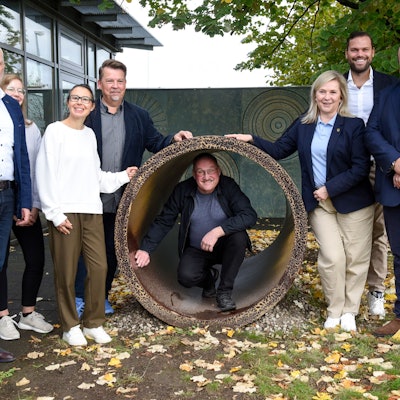 Auf dem Bild ist die Übergabe des Steinzeugrohrs zu sehen.