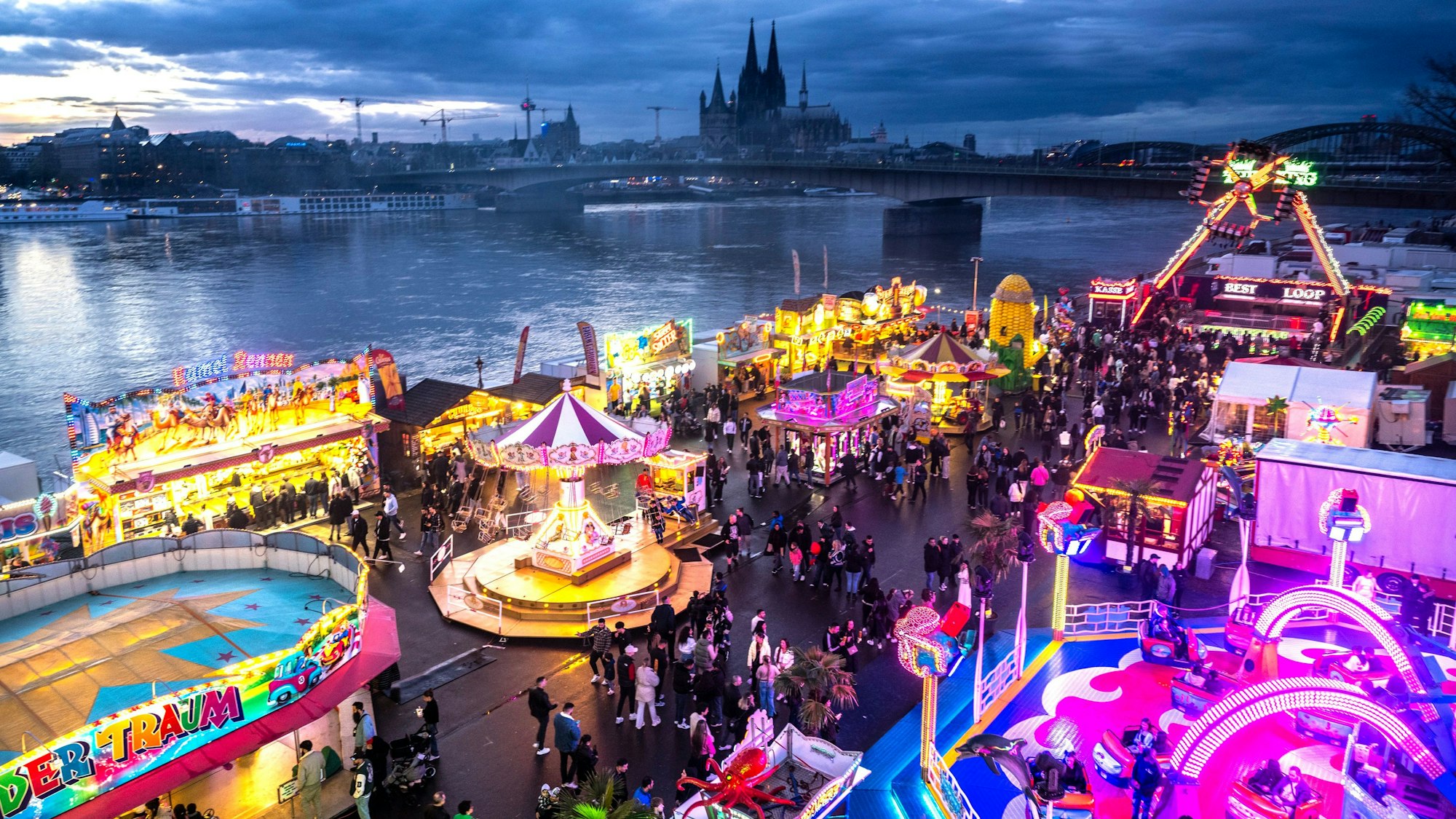 31.03.2024, Köln: Die Deutzer Kirmes leuchtet in der Abenddämmerung. Im Vorfeld hatte es auch Streitigkeiten um die Stromversorgung gegeben. Foto: Uwe Weiser