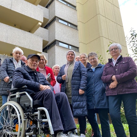 Menschen stehen vor einem Gebäude.