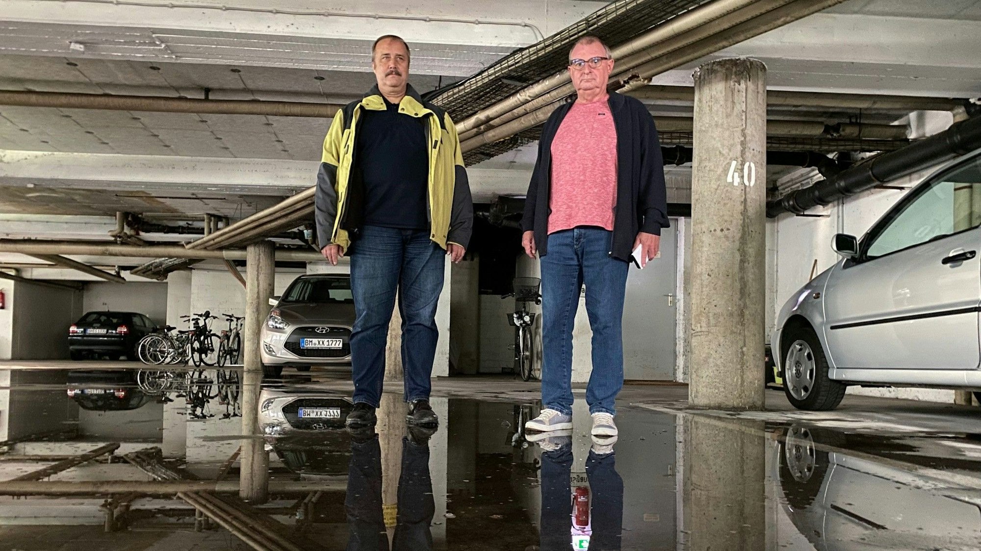 Zwei Männer stehen in einer Tiefgarage.