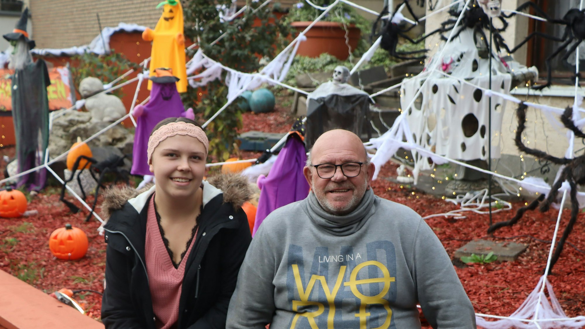 Manfred Wollsiefer und seine Nichte Joana Wollsiefer im Vorgarten. Bei Tag lässt sich die schaurige Stimmung bei bei Dunkelheit bereits erahnen.