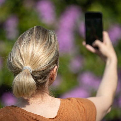 Eine Frau hält ein Smartphone in der Hand und macht ein Selfie.
