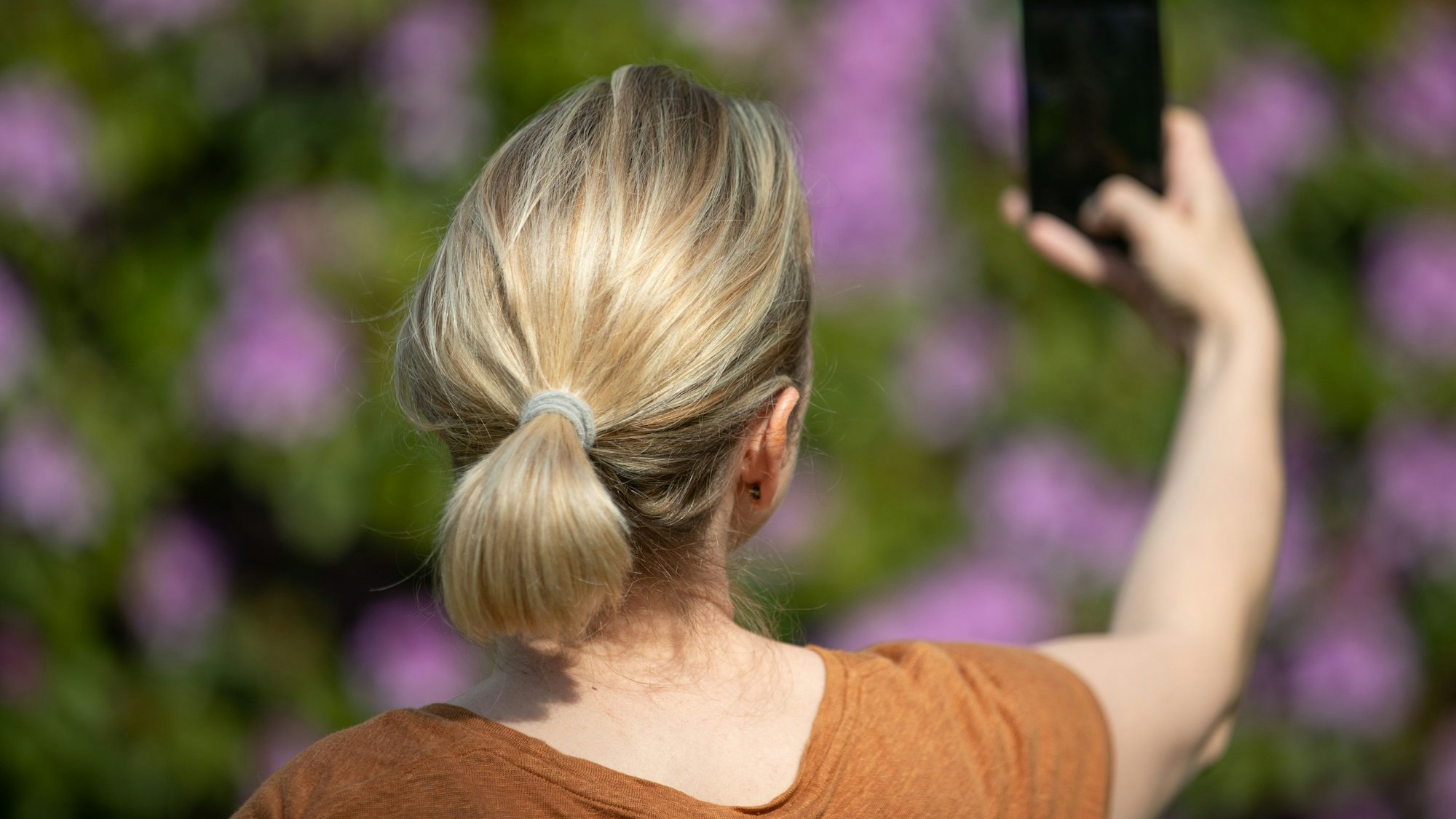 Eine Frau hält ein Smartphone in der Hand und macht ein Selfie.