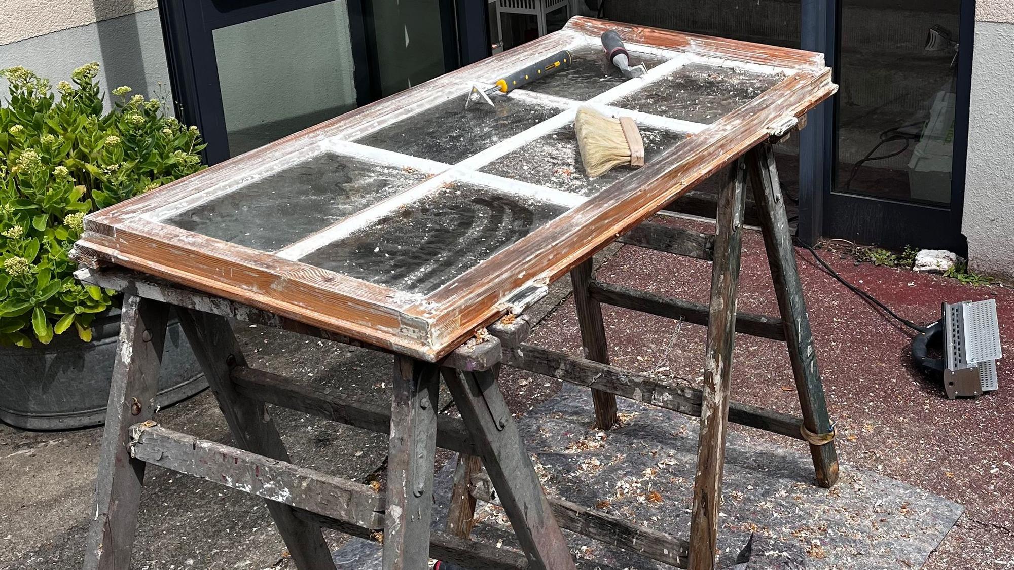 Zum Teil abgelacktes Holz-Sprossenfenster auf einem Bock