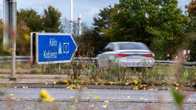 Ein Schild weist auf die Autobahn in Richtung Köln, ein Wagen biegt in die Richtung ab.