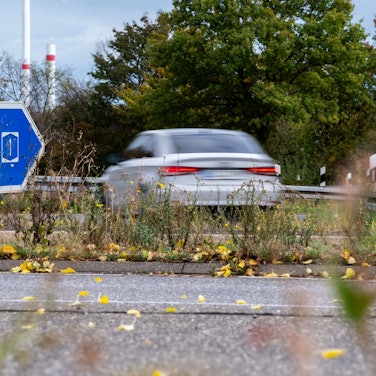 Ein Schild weist auf die Autobahn in Richtung Köln, ein Wagen biegt in die Richtung ab.