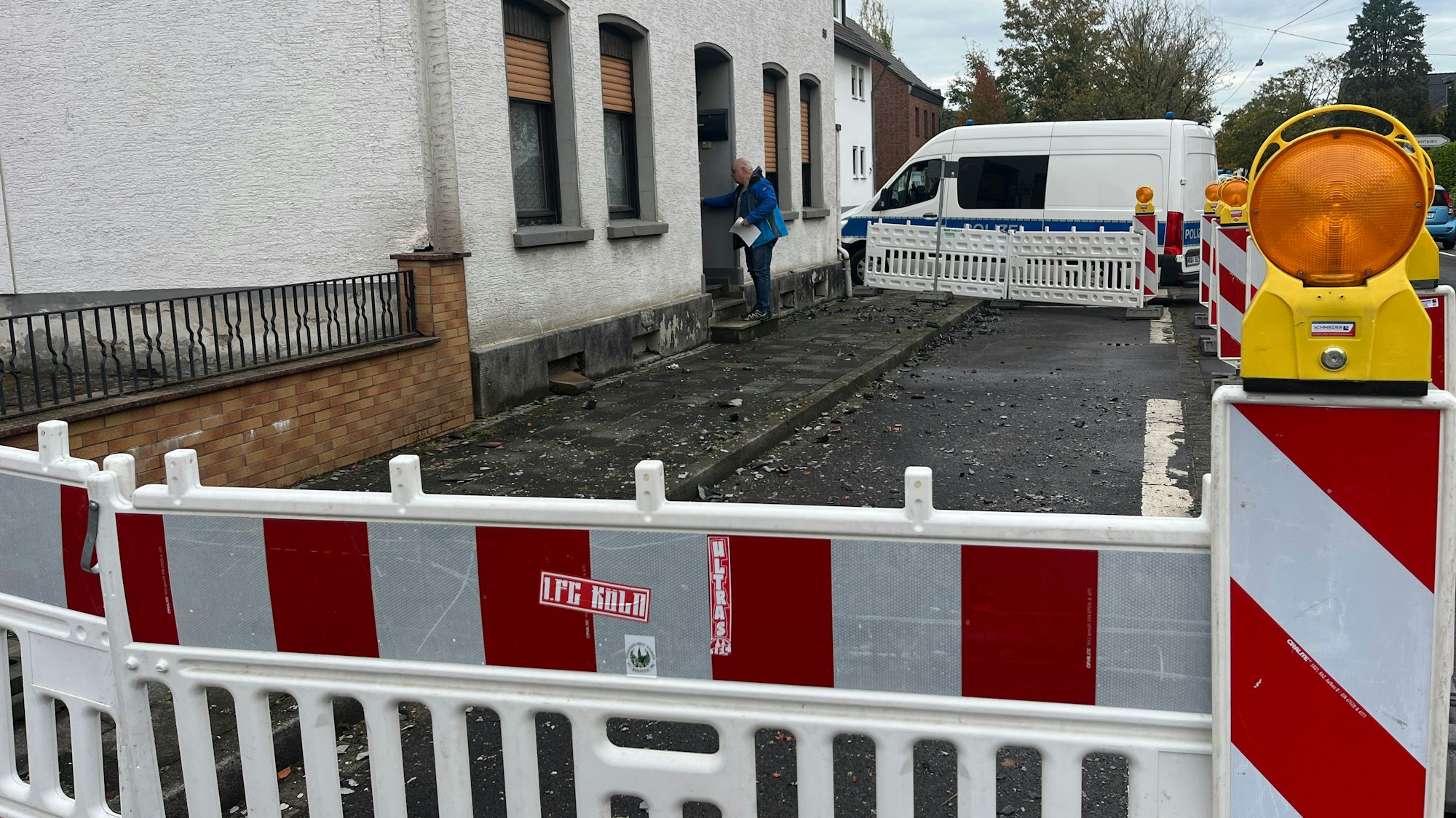 Ein Bauzaun steht vor einem ausgebrannten Haus, das ein Mann gerade betritt.