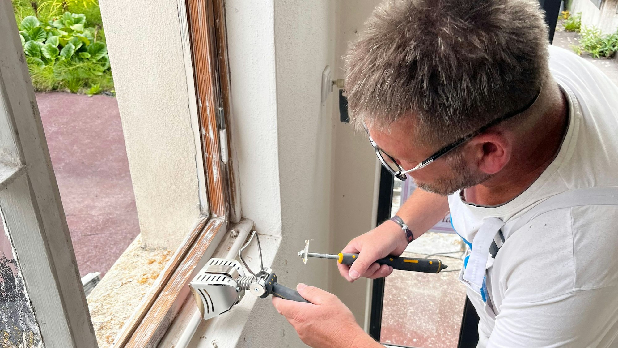 Malermeister Dirk Pabst arbeitet an einem alten Fensterrahmen.