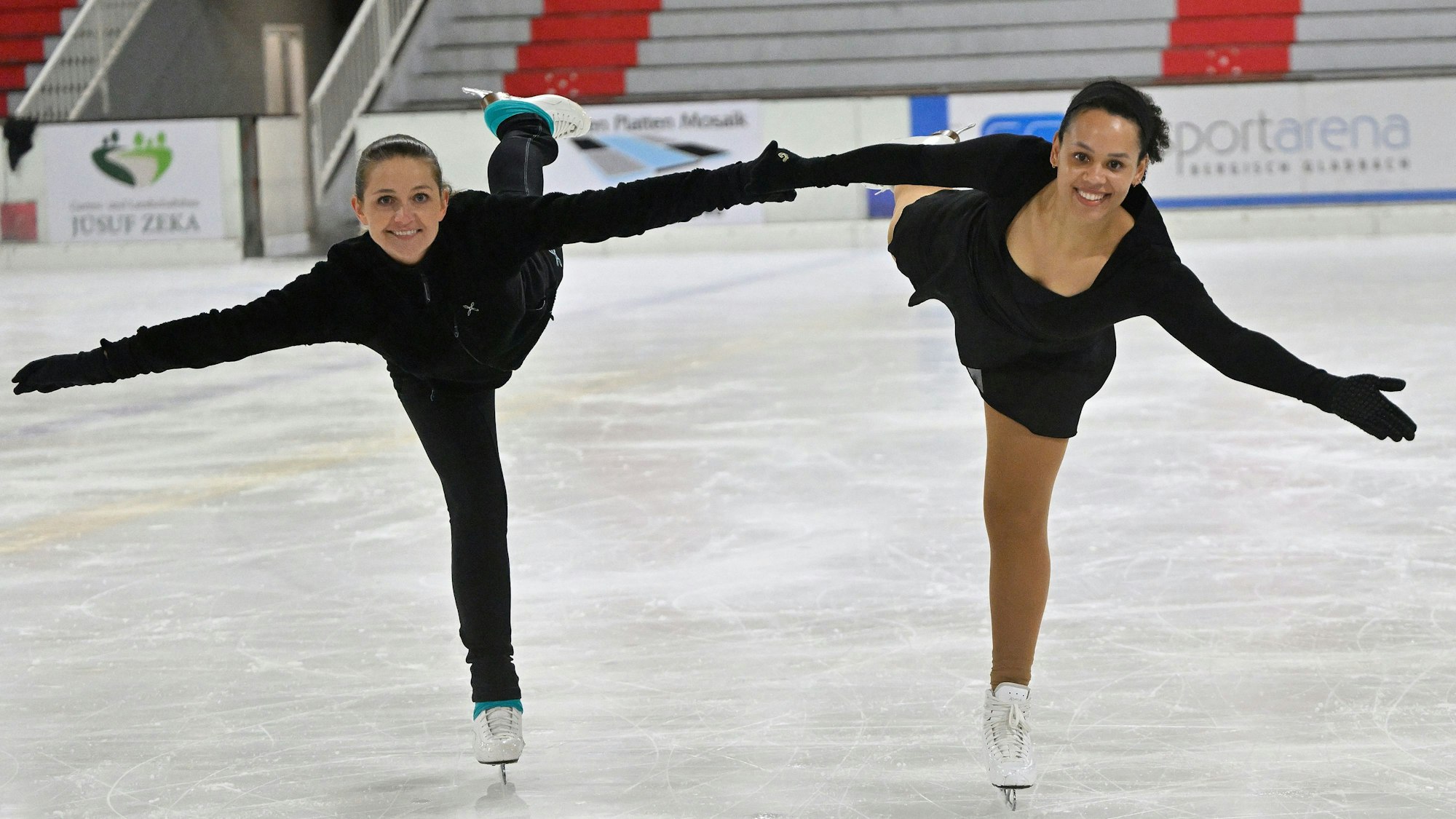 Zwei junge Frauen zeigen ein Kunststück auf Schlittschuhen.