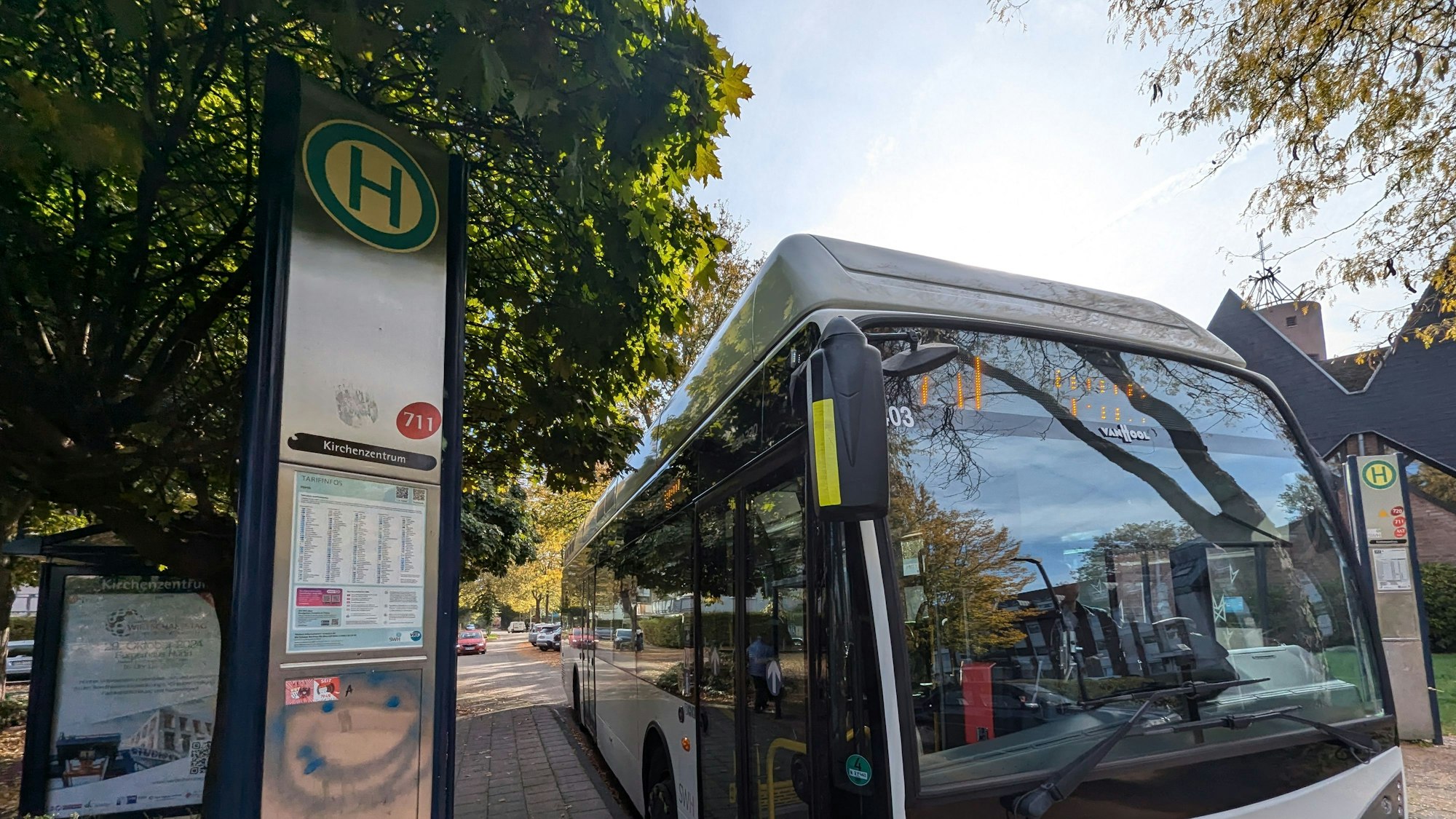 Das Foto zeigt einen Stadtbus an einer Bushaltestelle mit verbeulter Dreieckssäule.