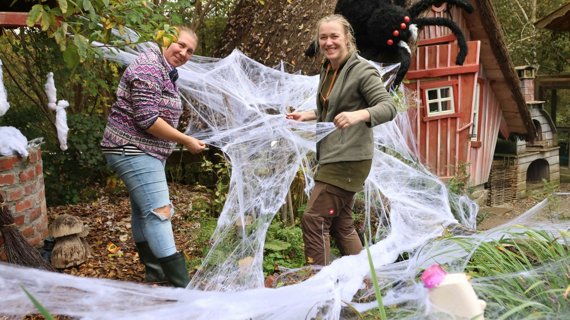 Die beiden Gärtnerinnen Caro (links) und Anne dekorieren im Affen- und Vogelpark in Reichshof-Eckenhagen den Hexengarten. Dort geht es jetzt schaurig schön, aber nicht unbedingt gruselig her. Unser Foto zeigt die Frauen bei der Arbeit, sie platzieren riesige Spinnennetze.