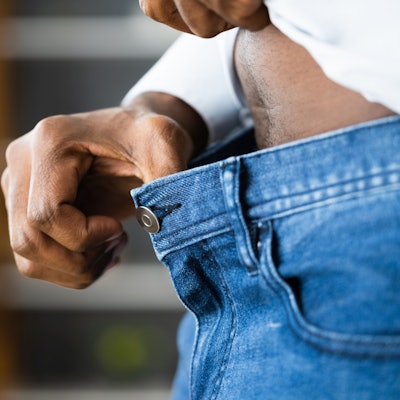 Eine Hand greift an den Hosenbund und weitet ihn.