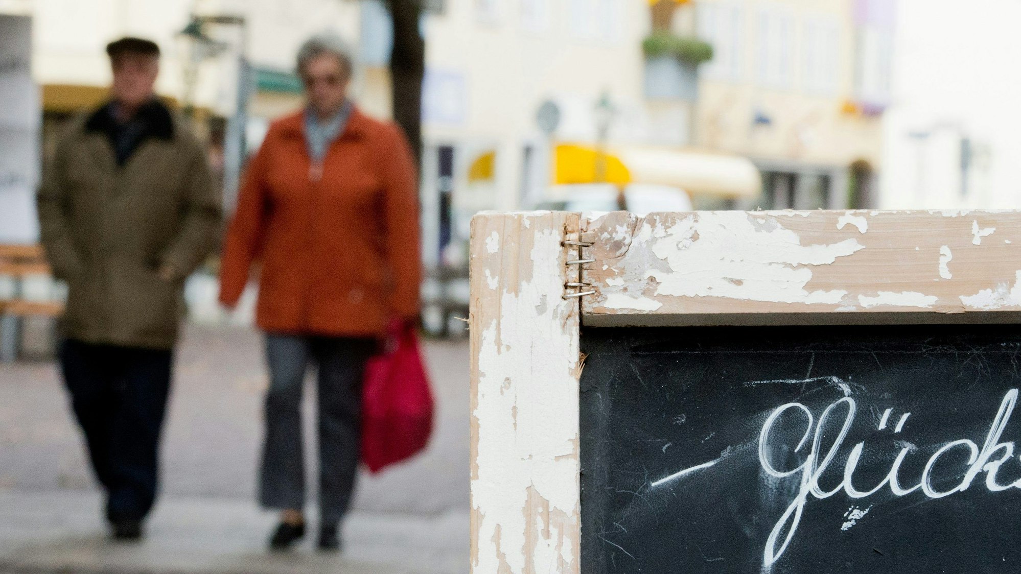 Ein älteres Paar geht am 05.11.2013 an einem Schild mit der Aufschrift "Glück" am Cafe "Glücksmoment" in Hannover (Niedersachsen) vorbei.