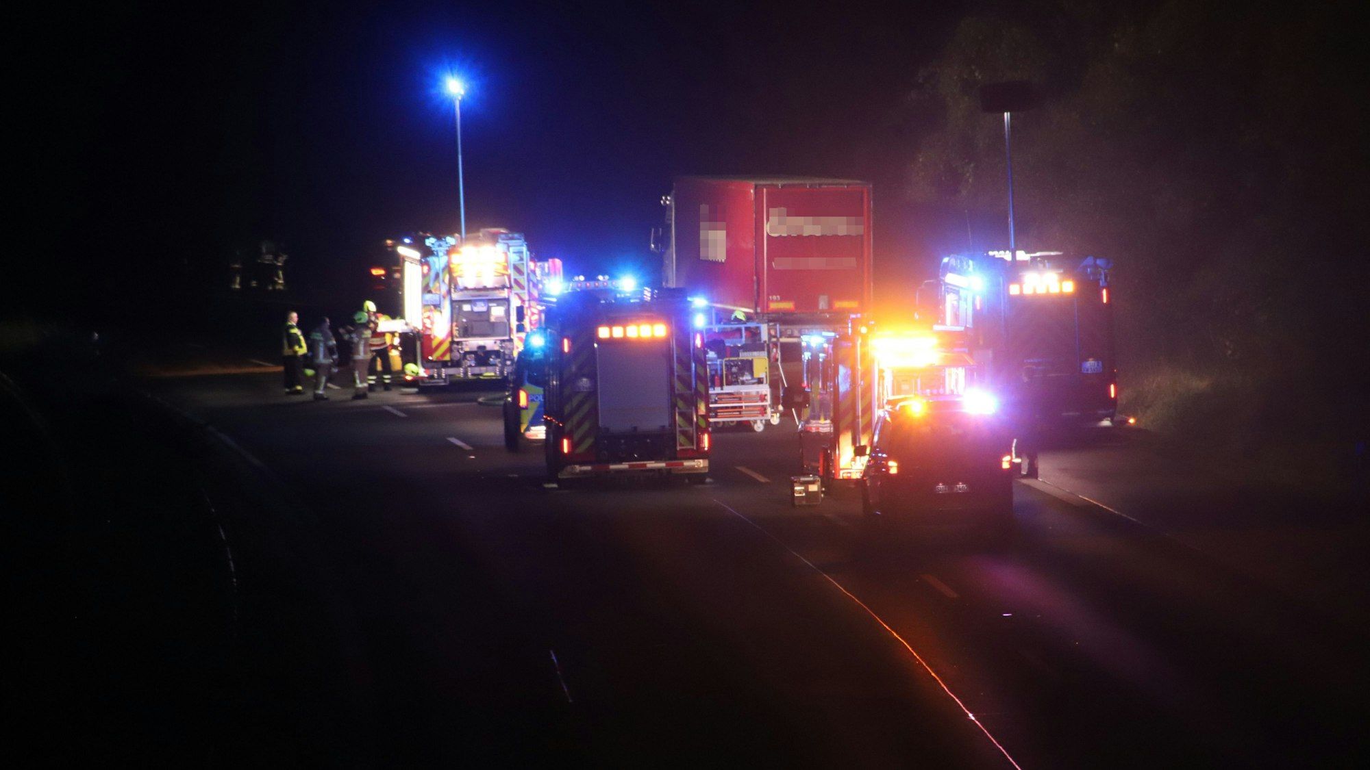 Feuerwehrautos stehen hinter und neben einem Lastwagen.