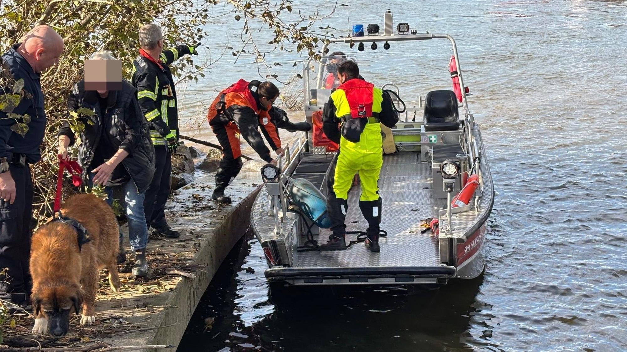 Die Feuerwehr Bonn steigt von einem Boot, daneben ein Hund und seine Besitzerin.
